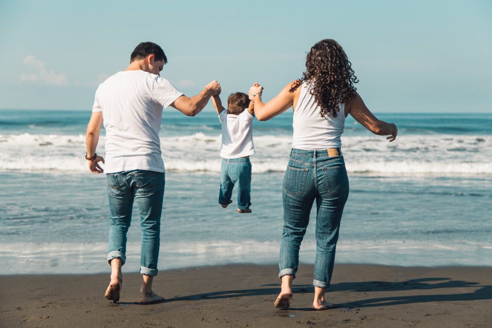 Parents joyfully playing with their baby on a sunny beach