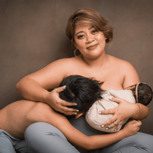 A mother sits with a serene smile while holding her two children—one breastfeeding and the other leaning close—capturing the intimacy of motherhood and family bonding.