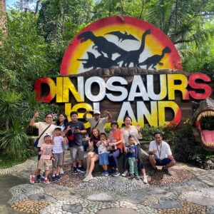 Family group posing in front of the Dinosaurs Island entrance sign in Clark, Pampanga
