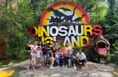 Family group posing in front of the Dinosaurs Island entrance sign in Clark, Pampanga