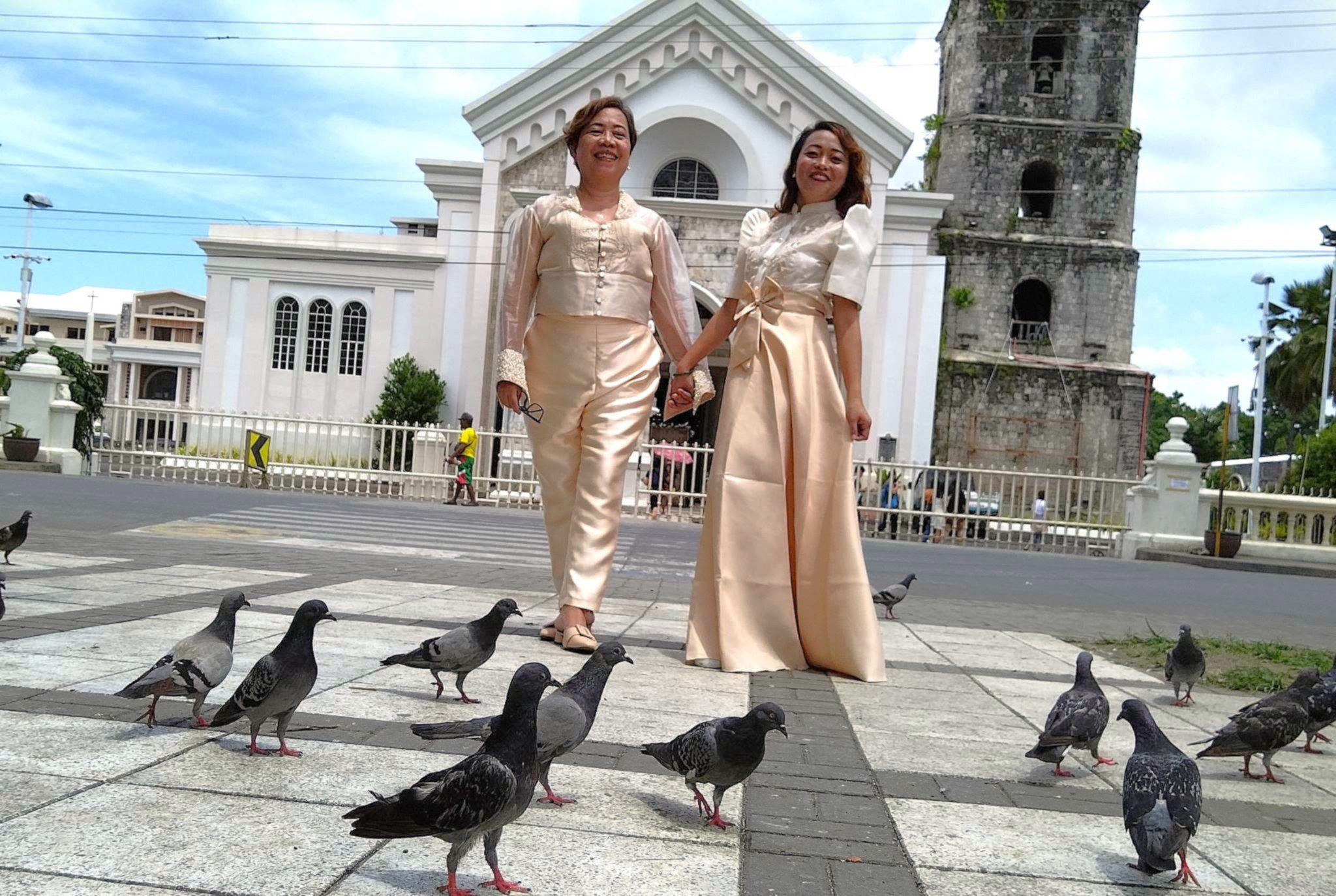 Faith Ido-Barrete and Margelyn Moncano-Cañon walking hand in hand in front of a church in Tagbilaran City, Bohol.