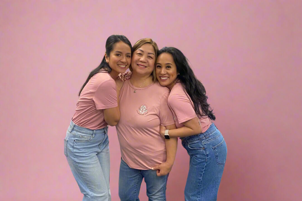 Dr. Kathleen Besas with her mother and sister wearing matching She is Rooted and Rising pink shirts.