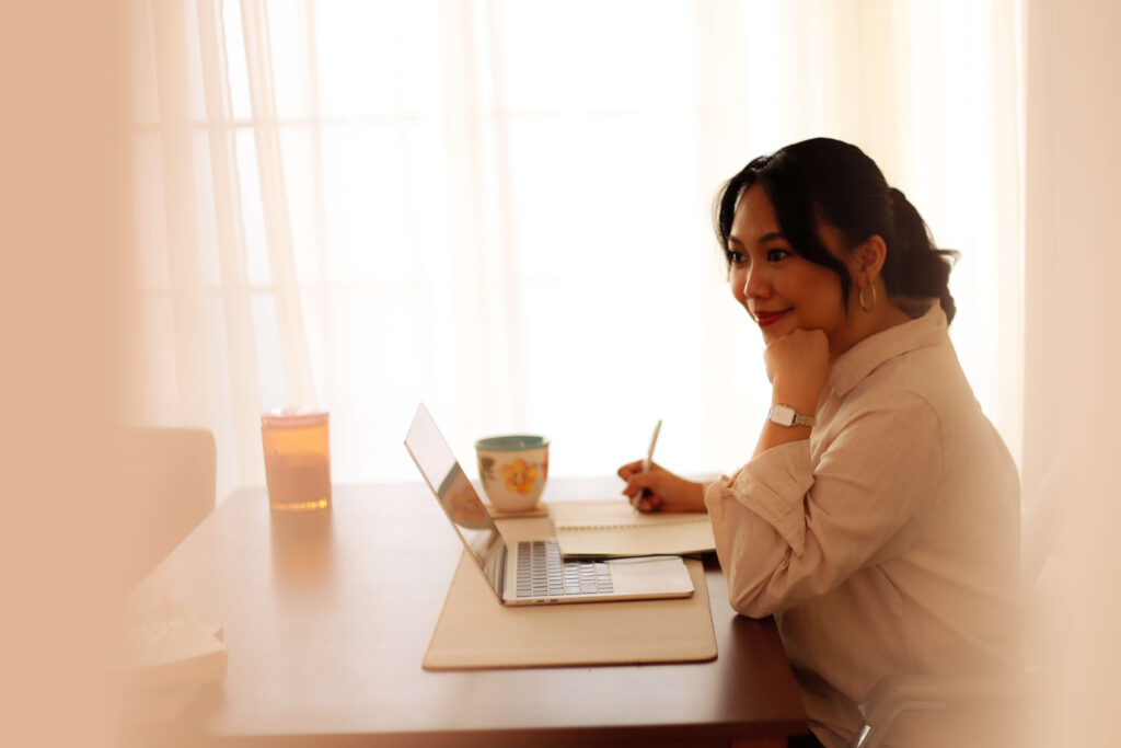 Denice Rabino working at her desk in a warm-lit home workspace