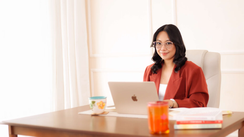 Denice Rabino working on her laptop at her desk in soft natural light